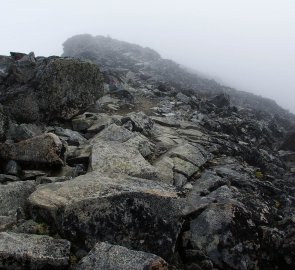 Postup v mlze po kamenité cestě směrem k hoře  Keilhaus topp 2 355 m n. m.