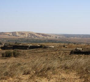 Za pevností a vrakem tanku mezi minovým polem je vidět Syrská hranice - Údolí slz na Golanských výšinách