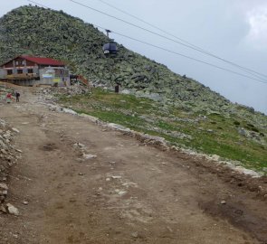 Kamenná chata pod Chopkom a za ní je vidět vrchol Chopku